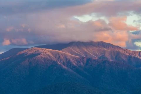 Australian Alps in orange sunset light and low clouds Stock Photos