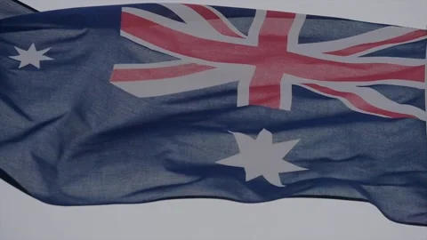 The Australian flag waving in a strong wind against a grey sky background. Stock Footage 150985521
