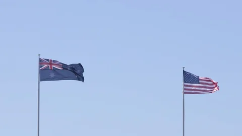 Australian flag waving in the wind next to an American flag Stock Footage 106591521