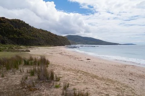 Australian sandy beach with soft waves and hills on the background Stock Photos