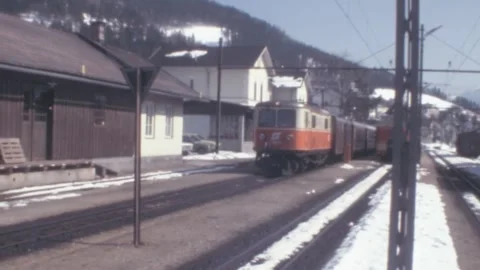 Austria - 1978: Retro 70s train stops at the station during winter with snow Stock Footage 277094977