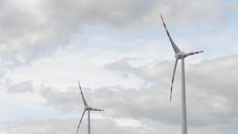 AUSTRIA - AUGUST 12, 2017. Two wind generators against cloudy sky Stock Photos