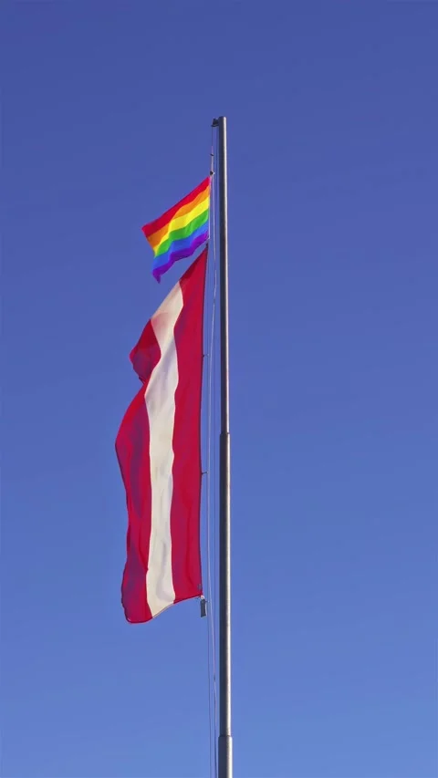 Austria Flag and Pride Rainbow Flag Blowing in Wind Towards Blue Sky, Vertical Stock Footage 310333930