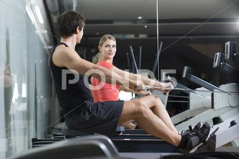 Austria, Klagenfurt, Man and woman exercising with rowing machine Stock Photos