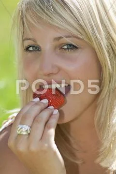 Austria, Salzburger Land, Altenmarkt, Young woman eating strawberry, portrait Stock Photos