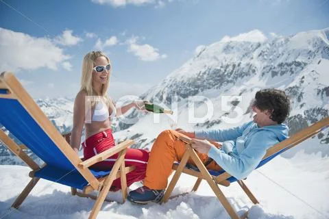 Austria, Salzburger Land, Couple sitting in deck chairs, woman holding champagne Stock Photos