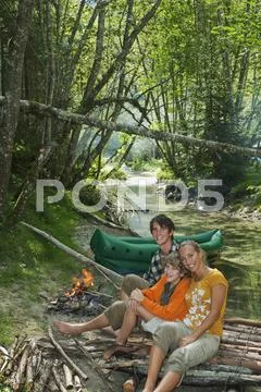 Austria, Salzburger Land, Family sitting at campfire, smiling Stock Photos