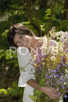 Austria, Salzburger Land, Woman holding bunch of wildflowers, smiling, close up Stock Photos