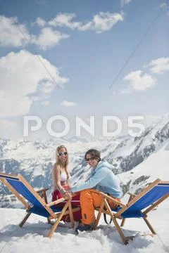 Austria, Salzburger Land, Young couple sitting in deck chairs, smiling, portrait Stock Photos