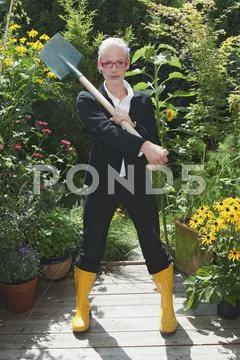 Austria, Salzburger Land, Young woman wearing boots, spade over shoulder Stock Photos
