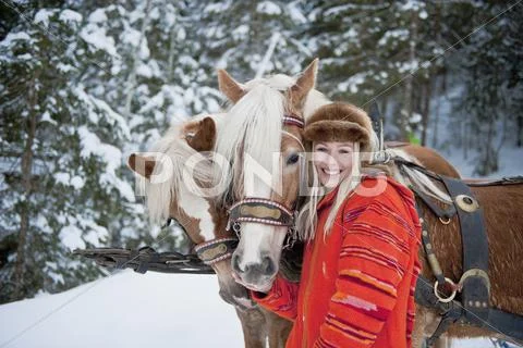 Austria, Salzburger Land, Young woman standing beside horses, smiling, portrait Stock Photos