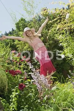 Austria, Woman in garden holding bunch of wildflowers, smiling Stock Photos