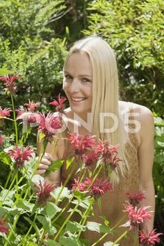 Austria, Woman smelling wildflowers, portrait Stock Photos