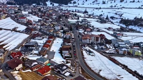 Austrian Alpine ski town with snow-covered roads and rooftops aerial in winter Vidéo 336187528