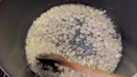 Autéing Diced Onions in a Pot with a Wooden Spoon Stock Footage 345304341