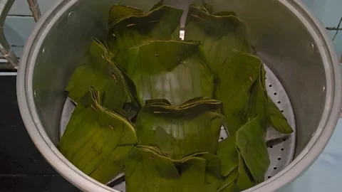 Authentic asian steamed wrapped in fresh green banana leaves placed in a me.. Stockbeeldmateriaal 309395418