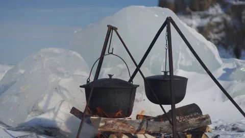 Authentic cast iron cauldrons cooking over open fire frozen Lake Baikal winter Video stock 316453735