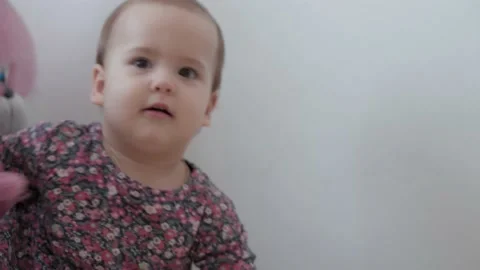 Authentic close up little infant child girl 1 year old in colorful dress playing Video stock 149358235