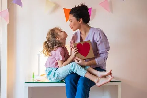 Authentic close-up of a mother and her daughter giving her mother a present. Stock Photos