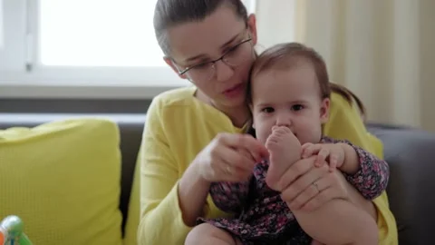 Authentic close up shot of young caucasian mother keep in arms, foot exercises Stock Footage 149441674