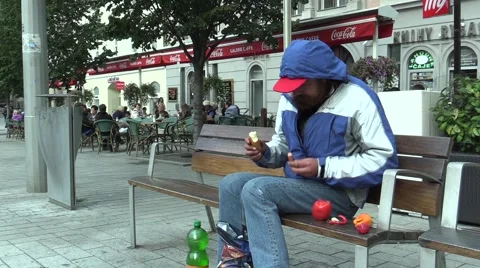 Authentic emotion homeless man sitting on a bench and eats food Stock Footage 56005451