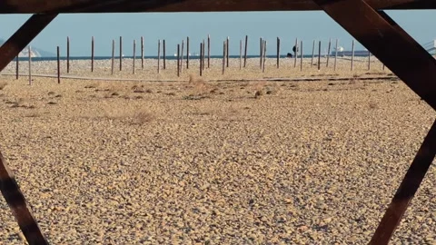 Authentic Empty Wooden Archway On Pebble Beach With Distant Man Walking Dog.. 스톡 동영상 330856920