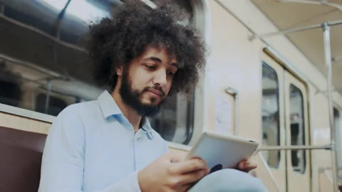 Authentic Hispanic Curly Handsome Man with Dark Skin Using Tablet PC in Subway Stock Footage 136069821