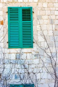 Authentic house with a stone wall, with beautiful old open windows and with g Stock Photos