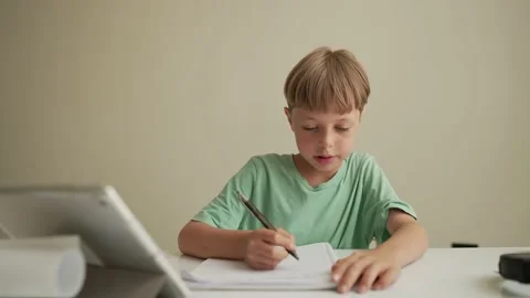 Authentic Kid doing online homework with friends at home, Child using tablet for Vídeos de archivo 194989748