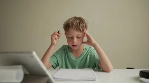 Authentic Kid doing online homework with friends at home, Child using tablet for Vidéo 195254022
