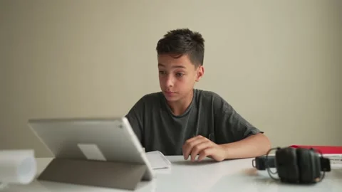 Authentic Kid doing online homework with friends at home, Child using tablet for 스톡 동영상 196742224