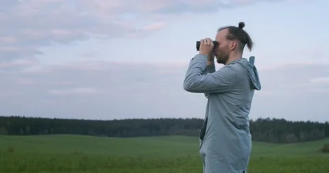 Authentic man looking into field glass on green field background copy space Stock Footage 134817359