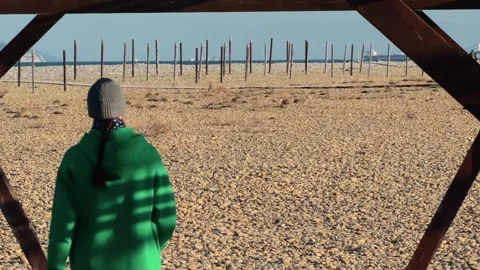 Authentic Man Walking Away Through Wooden Arch On Pebble Beach Toward Dista.. 스톡 동영상 330857377