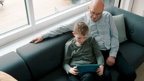 Authentic moment when two family members play with a digital tablet at home Stock Footage 105131849