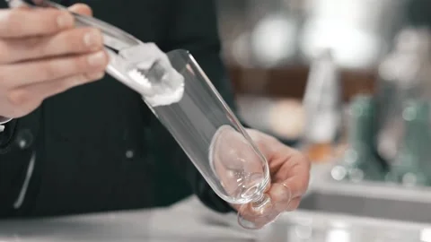 Authentic professional bartender puts ice in a nice long glass Stock Footage 193607774