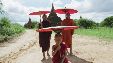 Authentic real monks In Bagan Mayanmar / Burma walking and shielding themselves Stock Footage 201096536