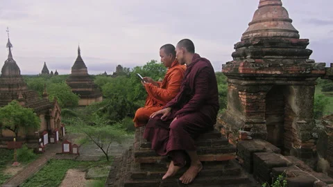 Authentic real monks, using smart phone to view video or photo of sunrise. Over Stock Footage 201094645