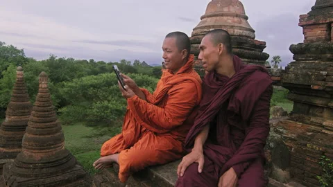 Authentic real monks, using smart phone to view video or photo of sunrise. Over Stock Footage 201096475