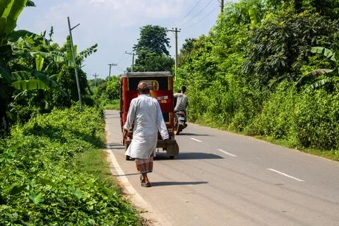 Authentic rural scene of a man pulling a tuk tuk along a road in Bangladesh Stock Photos