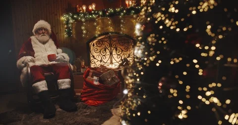 Authentic santa claus sitting in his rocker near christmas tree and srinking tea Stock Footage 111483990