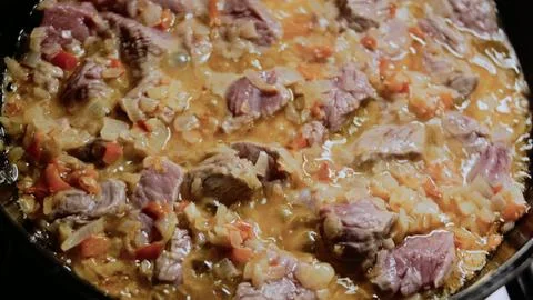 Authentic shallow focus scene: stirring tomato into the beef mixture Stock Photos