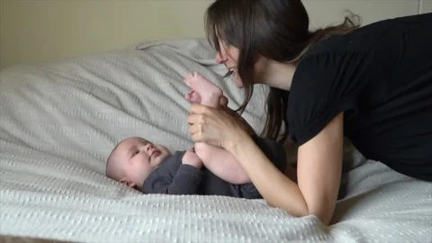 Authentic shot of young mother playing with her newborn baby laying in a bad. Stock Footage 263953655