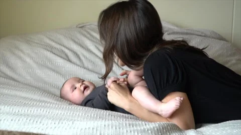 Authentic shot of young mother playing with her newborn baby laying in a bad. Stock Footage 263953761