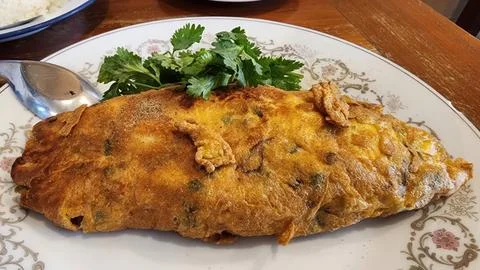 Authentic Thai Crispy Omelet Kai Jeow Garnished with Fresh Cilantro on Flor.. Stock Photos