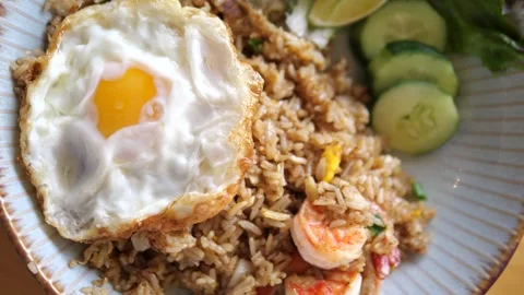 Authentic Thai shrimp fried rice served with crispy fried egg and cucumber Video stock 332144750