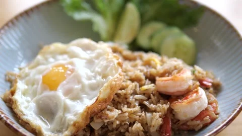Authentic Thai shrimp fried rice served with crispy fried egg and cucumber 스톡 동영상 332144757