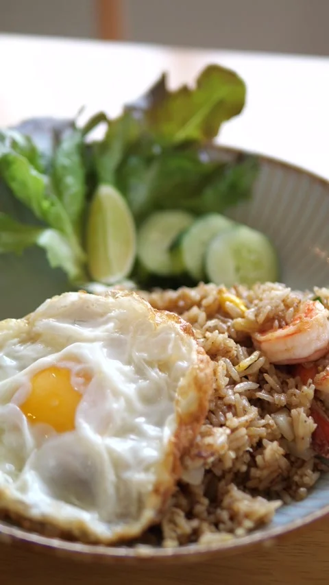 Authentic Thai shrimp fried rice served with crispy fried egg and cucumber 스톡 동영상 332144758