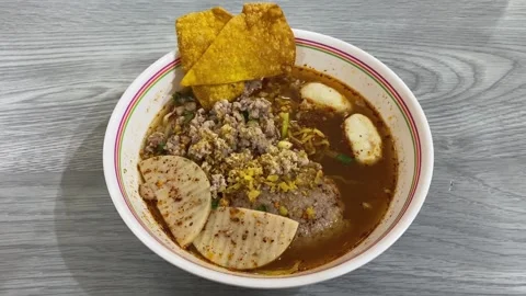 Authentic Thai Style Pork Spicy Egg Noodle Soup, Red Dried Chilies, Wonton Chips Stock Footage 222647110