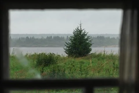 Authentic view of the river and meadow grass through the window of the old Stock Photos