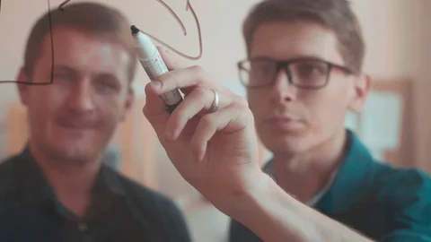 The authentic white man looking at the Board writing discuss the work. Goals and Stock Footage 95716554